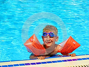 Happy boy swimming in outdoor pool in arm ruffles
