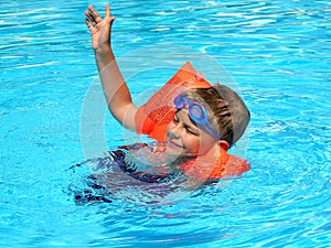 Happy boy swimming in outdoor pool in arm ruffles