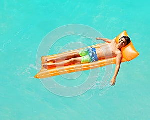 Happy boy swims on inflatable matrass in the sea