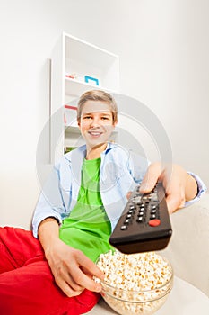 Happy boy switches remote control holding popcorn