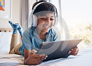 Happy boy, tablet and headphones on bed, smile or relax for streaming subscription, movie or funny video. Male child