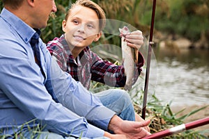 Happy boy teenager and father fishing together
