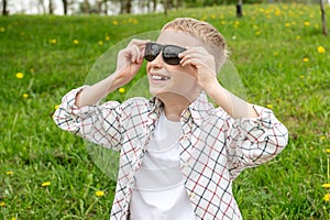 Happy boy without a tooth put on colorblind sunglasses and looks up