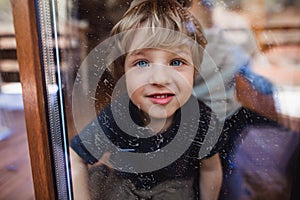 Happy boy with unrecognizable father cleaning windows at home, daily chores concept.