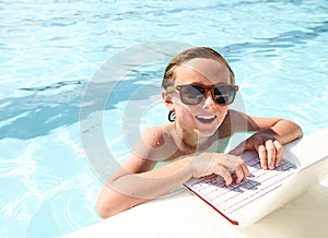 Happy boy using laptop in pool at summer resort