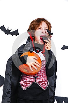 Happy boy in a vampire costume holding a pumpkin