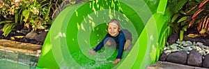 Happy boy on water slide in a swimming pool having fun during summer vacation in a beautiful tropical resort BANNER