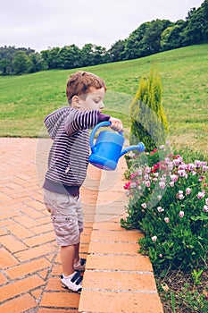 Happy boy watering flowers in the garden