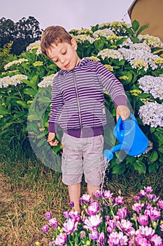 Happy boy watering flowers in the garden