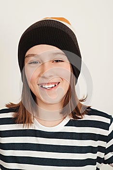 Happy boy wearing stylish woolen hat. Kid posing over on white background. Face portrait of eleven years old boy