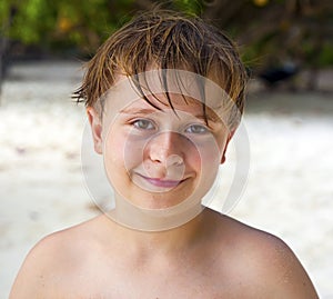 Happy boy with wet hair at the beach smiles and looks very self