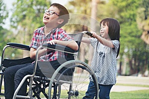 Happy boy in wheelchair with girl try drive a wheelchair of her