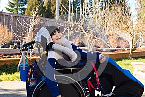 Happy boy in wheelchair outdoors smiling and laughing