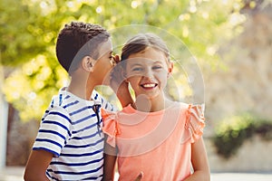 Happy boy whispering a secret in girls ear