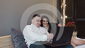 Happy boyfriend and girlfriend doing shopping online with laptop computer - Young people having fun buying presents in