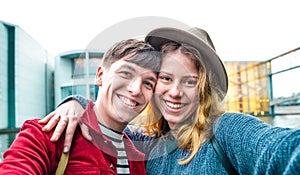 Happy boyfriend and girlfriend in love having genuine fun taking selfie at modern area in Berlin - Teenagers life style concept