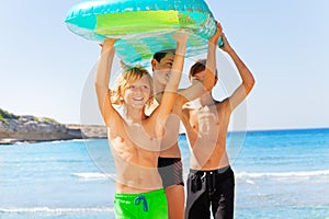 Happy boys with air mattress overhead on the beach