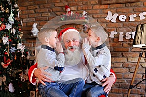 Happy boys brothers simultaneously whisper in ear of Christmas