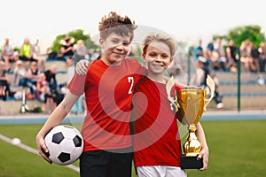 Happy boys friends teammates in soccer team winning golden trophy