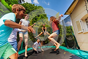Happy boys and girls jumping on outdoor trampoline photo