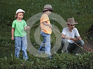 Happy boys go fishing on the river, children of the fisherman with a fishing rod on the shore of lake