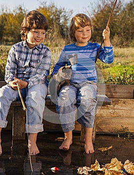 Happy boys go fishing on the river, Two children of the fisher with a fishing rod on the shore of lake