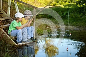 Happy boys go fishing on the river, Two children of the fisherman with a fishing rod on the shore of lake