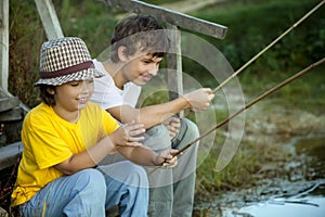 Happy boys go fishing on the river, Two children of the fisherman with a fishing rod on the shore of lake