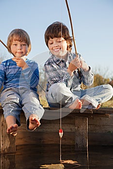 Happy boys go fishing on the river, Two children of the fisherman with a fishing rod on the shore of lake