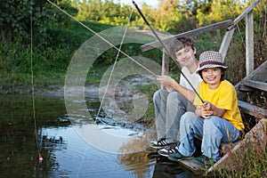 Happy boys go fishing on the river, Two children of the fisherman with a fishing rod on the shore of lake