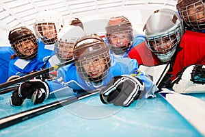 Happy boys in hockey uniform laying on ice rink