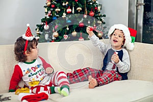 Happy boys playing with Christmas tree in the background