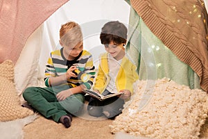 Happy boys reading book in kids tent at home