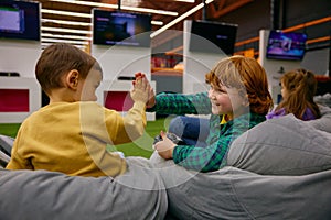 Happy boys siblings wining competition while playing video game in kids center photo