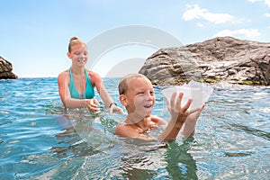Happy brave kids playing in sea with jellyfish Aurelia on summer holidays