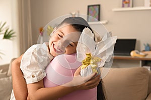 Happy brazilian kid with easter egg hugging woman at home