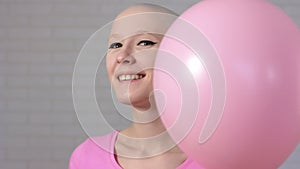 Happy breast cancer survivor woman appears out of pink ballons smiling and looking into the camera - breast cancer
