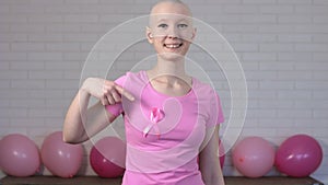 Happy breast cancer survivor woman pointing at breast cancer awareness ribbon - breast cancer awareness concept