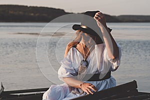 Happy bride in black hat in a boat on the river