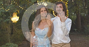 Happy bride and fiancee boasting engagement rings in summer evening. Portrait of happy loving young Caucasian couple