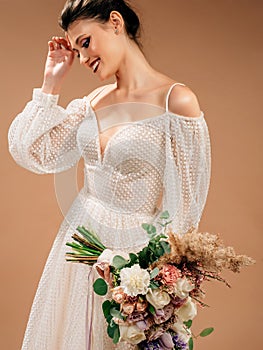 Happy bride in gorgeous wedding dress with long sleeves holds trendy bridal bouquet close up.