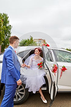 Happy bride and groom and beautiful wedding car in a sunny summer day