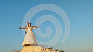 Happy bride and groom dream about flying. loving couple on white mountain hold hands and fly against blue sky. Honeymoon