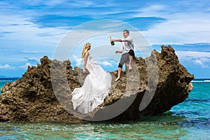 Happy bride and groom having fun on a tropical beach under the p