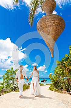 Happy bride and groom having fun on a tropical beach under the p