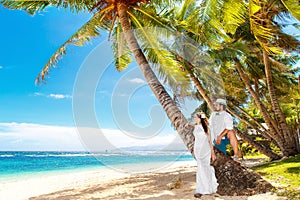 Happy bride and groom having fun on a tropical beach under palm