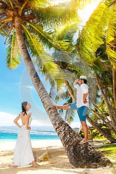 Happy bride and groom having fun on a tropical beach under palm