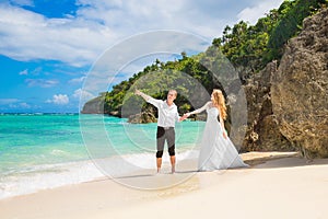 Happy Bride and Groom having fun on the tropical beach. Wedding