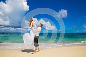 Happy bride and groom having fun on a tropical beach. Wedding an