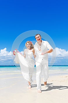 Happy bride and groom having fun on a tropical beach. Wedding an